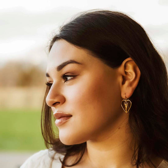 Model wearing Symbol of love gold heart soulmate earrings